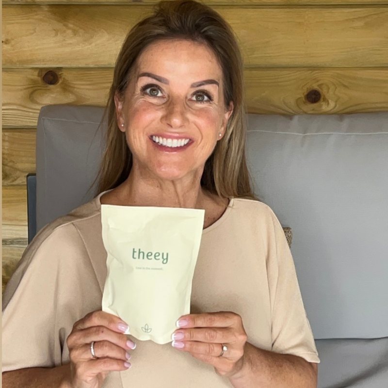 Theey-klant houdt lachend een theey-zak vast