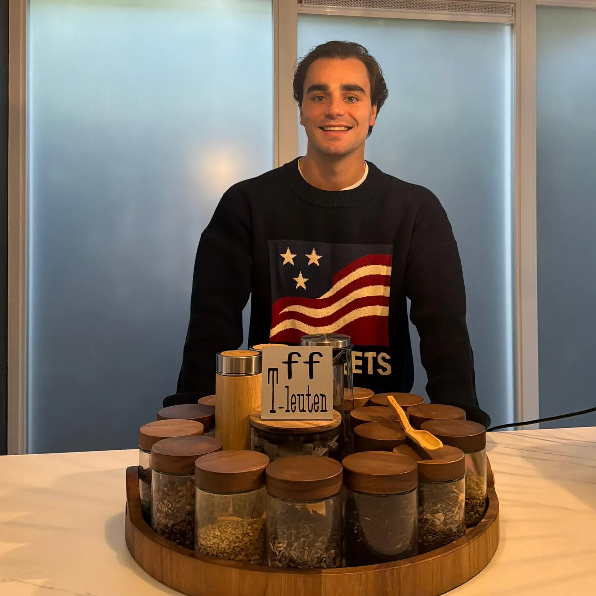 Ruben achter de keukentafel met een plank vol potten losse kruiden